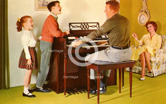 Family singing around a Wurlitizer organ as father plays, De Kalb, Illinois, USA, 1962. Artist: Unknown