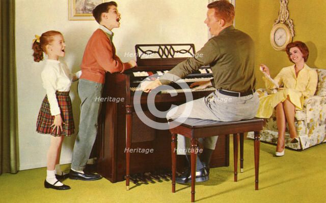Family singing around a Wurlitizer organ as father plays, De Kalb, Illinois, USA, 1962. Artist: Unknown