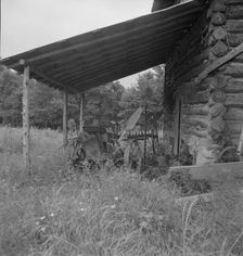 Farm machinery drawn under cover of old tobacco barn, Person County, North Carolina, 1939. Creator: Dorothea Lange