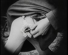 Fashionable Lady Sitting in a Garden, Adjusting Dials on a Miniature Wireless Radio in Her..., 1922. Creator: British Pathe Ltd