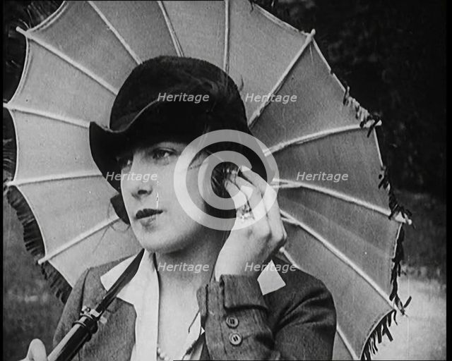 Fashionable Lady Sitting in a Garden Wearing Headphones and Carrying a Parasol, 1922. Creator: British Pathe Ltd.
