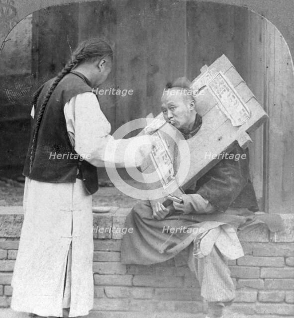 Feeding a prisoner wearing a cangue, China, 1902. Artist: CH Graves
