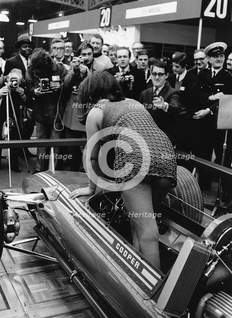 Female model climing in to Cooper F5000 at 1969 Racing Car show. Creator: Unknown.