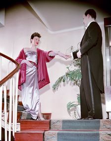 Female model shows an evening dress, with a male model in a tailcoat, Sweden, 1950s. Creator: Göran Algård