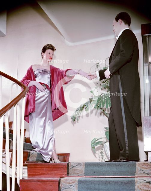 Female model shows an evening dress, with a male model in a tailcoat, Sweden, 1950s. Creator: Göran Algård.