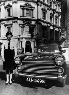 Female chauffeur standing by a 1964 Morris Oxford, 1964