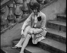 Female Civilian Doing up the Buttons of Her Leather Boots Sitting on Steps Outdoors, 1920. Creator: British Pathe Ltd