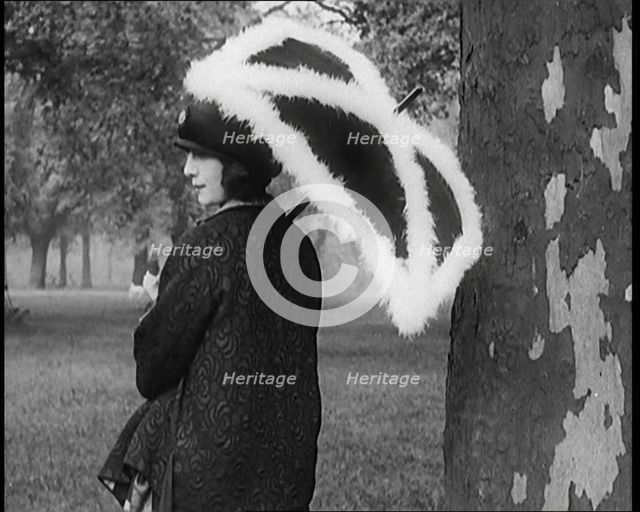 Female Civilian Dressed Glamorously Holding a Fur Trimmed Parasol in a Park, 1920. Creator: British Pathe Ltd.