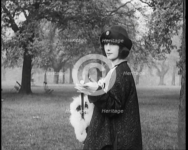 Female Civilian Dressed Glamorously Holding a Fur Trimmed Parasol in a Park, 1920. Creator: British Pathe Ltd.