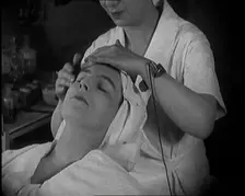 Female Civilian Having Her Face Massaged by Another Female Civilian Wearing an Electric, ... 1920. Creator: British Pathe Ltd