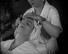 Female Civilian Having Her Face Massaged by Another Female Civilian Wearing an Electric, ... 1920. Creator: British Pathe Ltd