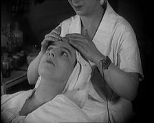 Female Civilian Having Her Face Massaged by Another Female Civilian Wearing an Electric, ... 1920. Creator: British Pathe Ltd