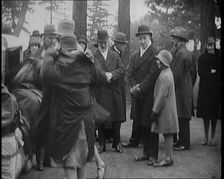 Female Civilian Helping Another Female Civilian to Put on a Coat in Front of a Car and a..., 1920. Creator: British Pathe Ltd