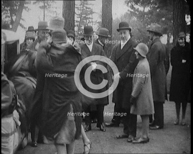 Female Civilian Helping Another Female Civilian to Put on a Coat in Front of a Car and a..., 1920. Creator: British Pathe Ltd.