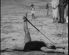 Female Civilian Laying on the Sand Exercising with an Elastic Band on a Beach, 1920. Creator: British Pathe Ltd