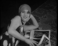 Female Civilian Laying on a Carpet Wearing a Swimsuit and Sandals Reading a Magazine, 1920. Creator: British Pathe Ltd