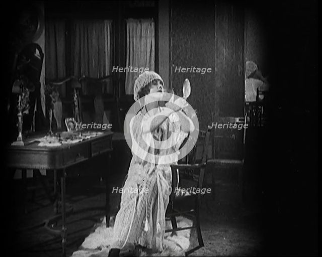 Female Civilian Seating in Front of a Dressing Table Wearing a Nightgown and Boudoir Cap..., 1920. Creator: British Pathe Ltd.