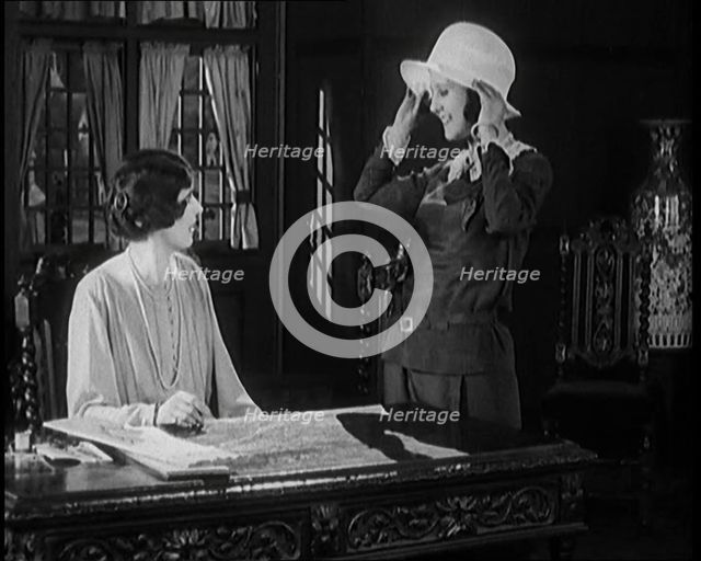 Female Civilian Trying a Hat in Front of Another Female Civilian, 1920. Creator: British Pathe Ltd.