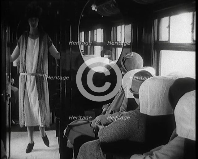 Female Civilian Wearing a Dress and Hat Modelling in Front of a Small Audience Inside a..., 1920. Creator: British Pathe Ltd.