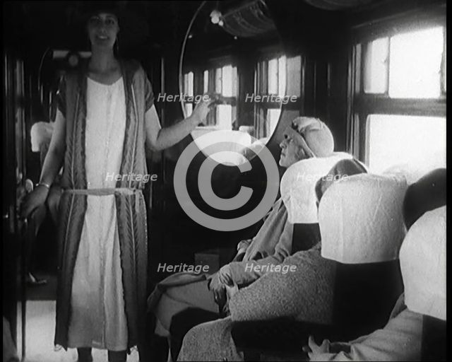 Female Civilian Wearing a Dress and Hat Modelling in Front of a Small Audience Inside a..., 1920. Creator: British Pathe Ltd.