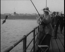 Female Civilian Wearing a Hat with a Dark Ribbon Fishing from a Pier, 1920. Creator: British Pathe Ltd