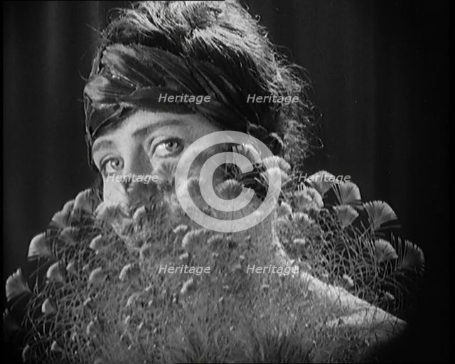 Female Civilian Wearing a Headband Hiding Her Face Behind a Feathers Fan, 1920. Creator: British Pathe Ltd.