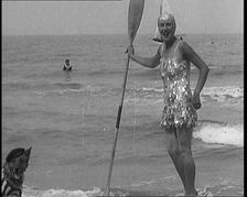 Female Civilian Wearing a Sequinned Swimsuit with a Dog in a Striped Shirt and Beret on a Canoe,1920 Creator: British Pathe Ltd