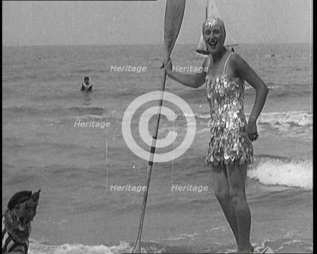 Female Civilian Wearing a Sequinned Swimsuit with a Dog in a Striped Shirt and Beret on a Canoe,1920 Creator: British Pathe Ltd.