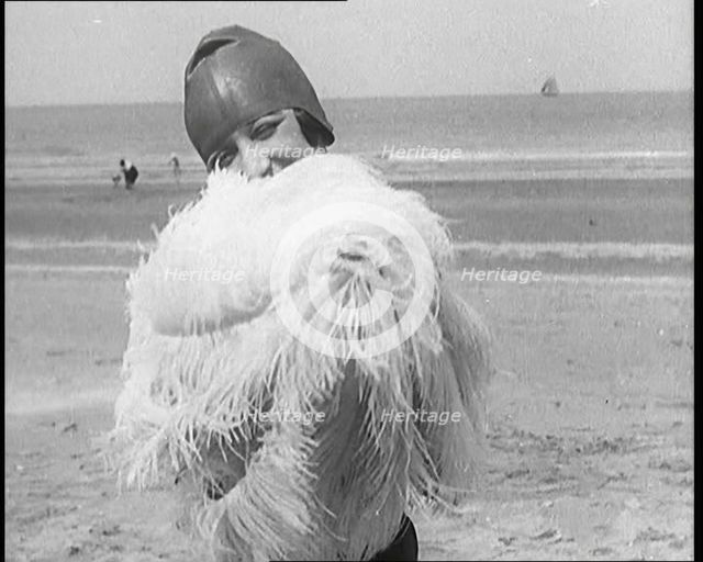 Female Civilian Wearing a Swimsuit Holding a Feathered Parasol at the Beach, 1920. Creator: British Pathe Ltd.