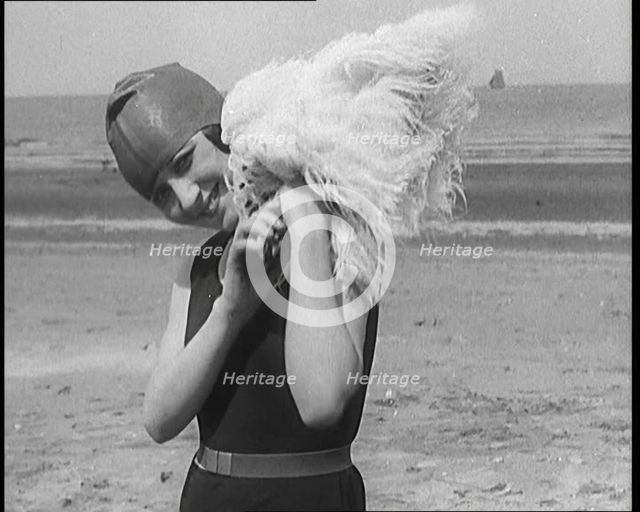 Female Civilian Wearing a Swimsuit Holding a Feathered Parasol at the Beach, 1920. Creator: British Pathe Ltd.