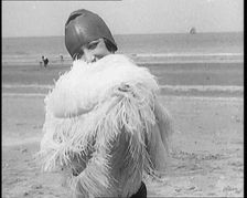 Female Civilian Wearing a Swimsuit Holding a Feathered Parasol at the Beach, 1920. Creator: British Pathe Ltd