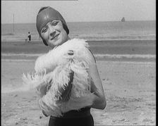 Female Civilian Wearing a Swimsuit Holding a Feathered Parasol at the Beach, 1920. Creator: British Pathe Ltd