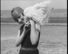 Female Civilian Wearing a Swimsuit Holding a Feathered Parasol at the Beach, 1920. Creator: British Pathe Ltd