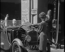 Female Civilians Working Petrol Pumps in a Garage and Filling up a Car, 1931. Creator: British Pathe Ltd