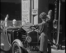 Female Civilians Working Petrol Pumps in a Garage and Filling up a Car, 1931. Creator: British Pathe Ltd