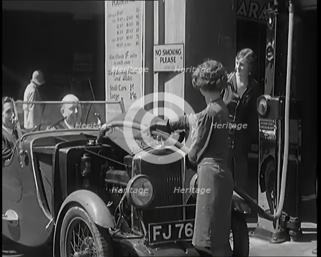 Female Civilians Working Petrol Pumps in a Garage and Filling up a Car, 1931. Creator: British Pathe Ltd.