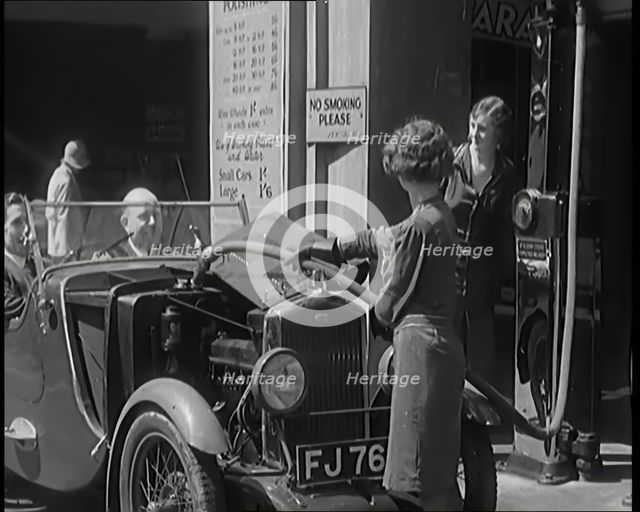 Female Civilians Working Petrol Pumps in a Garage and Filling up a Car, 1931. Creator: British Pathe Ltd.