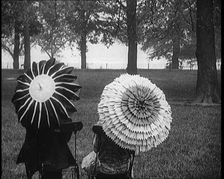 Female Civilians Holding Ornate Parasols in a Park, 1920. Creator: British Pathe Ltd