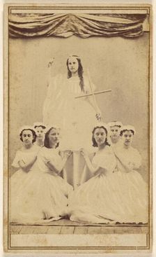 Female group portrait, six in white gowns kneeling, one standing holding a cross, about 1865. Creator: Unknown