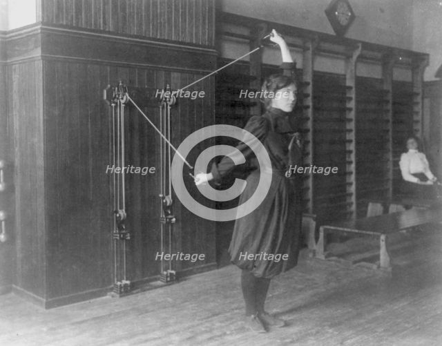 Female student exercising with a wall-mounted device using ropes and..., Washington, DC, (1899?). Creator: Frances Benjamin Johnston.