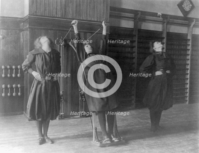 Female students exercising, one with a wall-mounted device using ropes..., Washington, D.C., (1899?) Creator: Frances Benjamin Johnston.