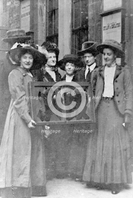 Five suffragettes holding a broken window in its frame, 1912. Creator: Unknown.