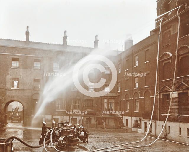 Firemen demonstrating hoses worked by a petrol motor pump, London Fire Brigade Headquarters, 1909. Artist: Unknown.