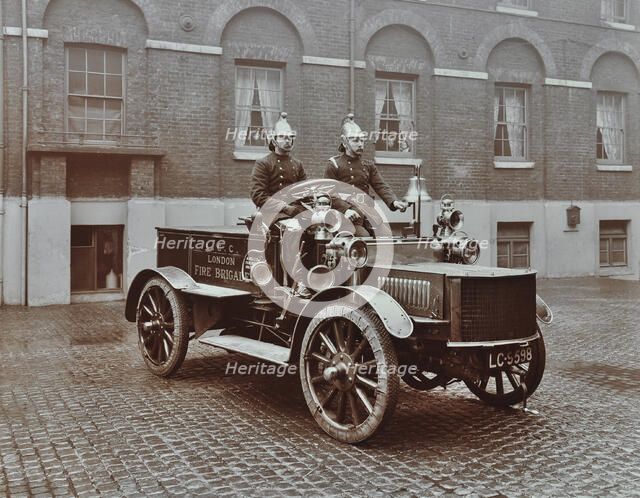 Firemen in brass helmets aboard a motor hose tender, London Fire Brigade Headquarters, London, 1909. Artist: Unknown.
