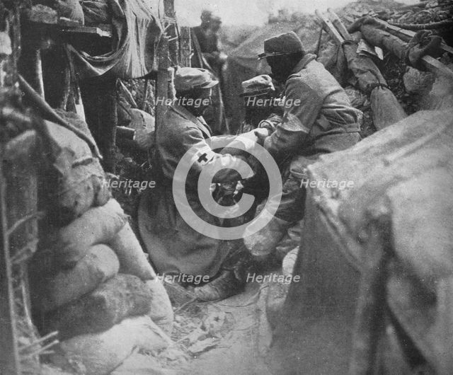 'First aid to a wounded man in one of the French trenches', 1915. Artist: Unknown.