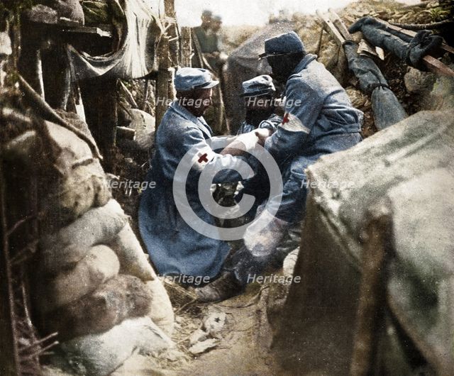 'First aid to a wounded man in one of the French trenches', 1915. Artist: Unknown.