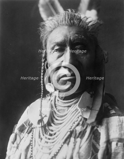 Fish Shows, an Apsaroke Indian, head-and-shoulders portrait, facing front, pompadour..., c1908. Creator: Edward Sheriff Curtis.