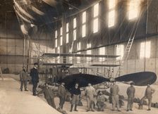 France. Hangar with the cockpit of an airship and a group of mechanics and pilots, 1900s