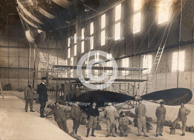 France. Hangar with the cockpit of an airship and a group of mechanics and pilots, 1900s.