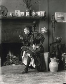 Frances Benjamin Johnston, full-length portrait, seated in front of fireplace, facing left..., 1896. Creator: Frances Benjamin Johnston